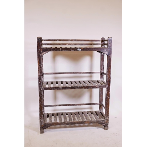 1235 - An Indian teak three tier open rack, with distressed paint traces, 36