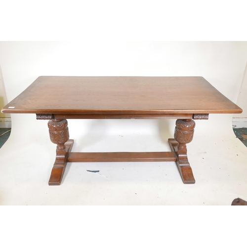 1250 - A plank top oak refectory table with bulbous carved end supports, 66