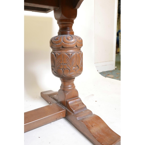 1250 - A plank top oak refectory table with bulbous carved end supports, 66