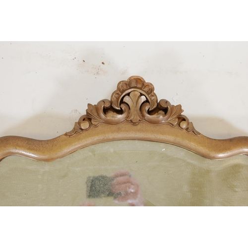 1268 - A giltwood wall mirror with shaped frame and carved crest, 22