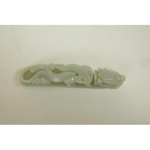 13 - A Chinese celadon jade belt buckle with carved dragon decoration, 5½