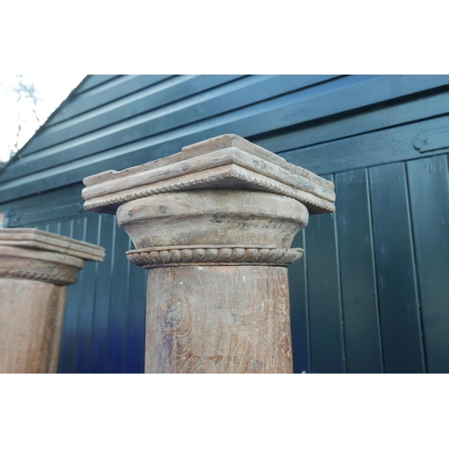 1300 - Architectural salvage: A pair of Indian teak columns with carved capitals, mounted on carved stone b... 