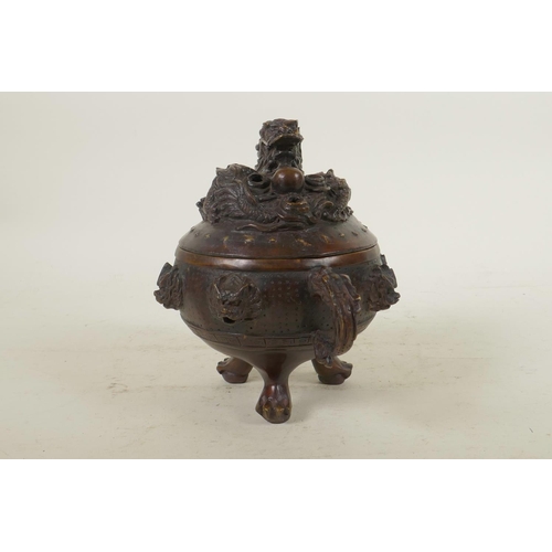 135 - A Chinese bronze censer and cover with two dragon shape handles, tripod pawed feet, dragon mask deco... 