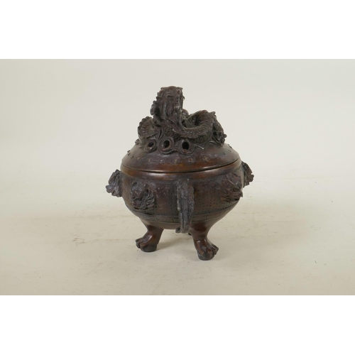 135 - A Chinese bronze censer and cover with two dragon shape handles, tripod pawed feet, dragon mask deco... 