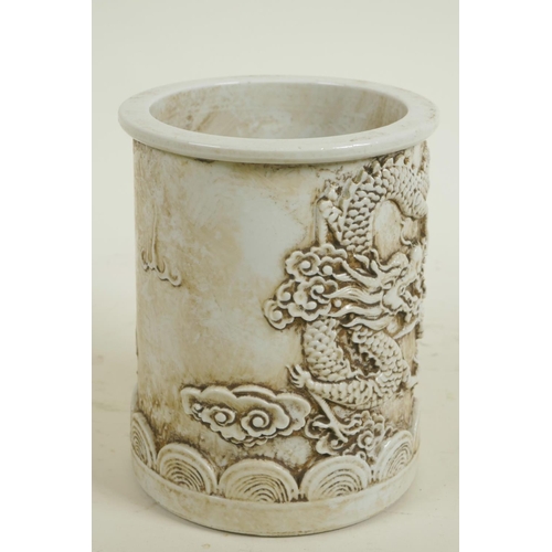 163 - A Chinese white glazed porcelain brush pot with embossed dragon decoration, 5½