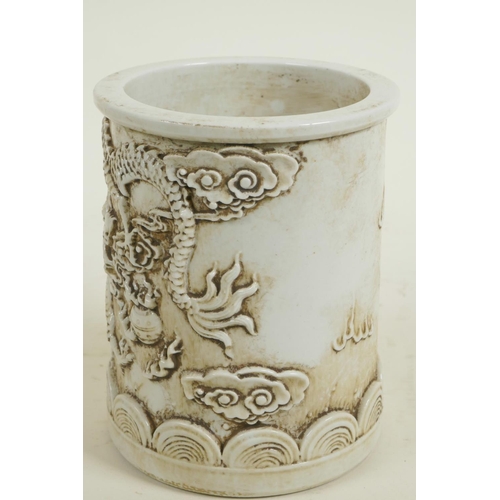 163 - A Chinese white glazed porcelain brush pot with embossed dragon decoration, 5½