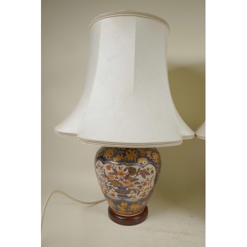 182 - A pair of Chinese pottery table lamps on wood stands with white silk shades, 20