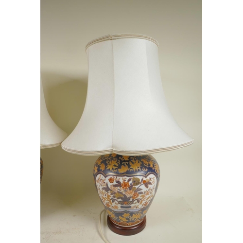 182 - A pair of Chinese pottery table lamps on wood stands with white silk shades, 20