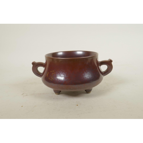 185 - A Chinese copper glazed porcelain censer with two handles, raised on tripod supports, impressed seal... 