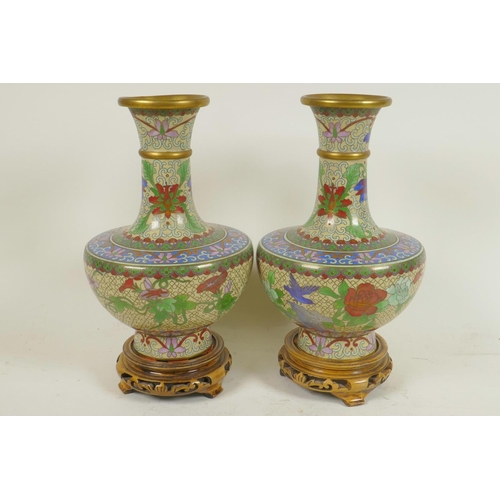 241 - A pair of Chinese cloisonne vases decorated with flowers, on carved wood stands, 9