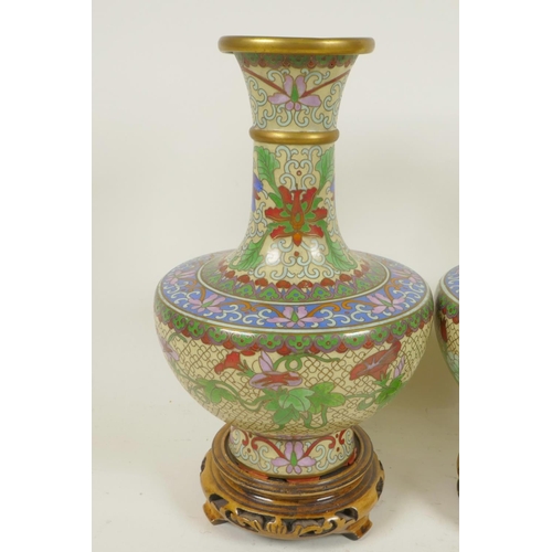 241 - A pair of Chinese cloisonne vases decorated with flowers, on carved wood stands, 9