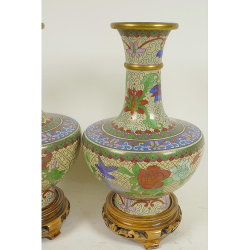 241 - A pair of Chinese cloisonne vases decorated with flowers, on carved wood stands, 9