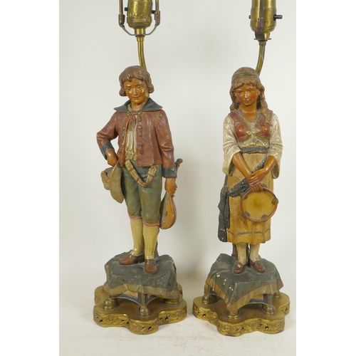 266 - A pair of Continental terracotta lamp bases of male and female musicians dressed in traditional cost... 