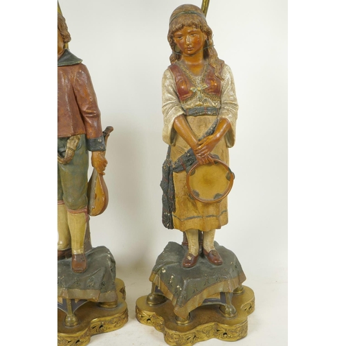 266 - A pair of Continental terracotta lamp bases of male and female musicians dressed in traditional cost... 