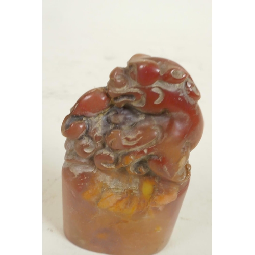 284 - A small Chinese carved soapstone seal, the top carved as a mythical beast, 2½