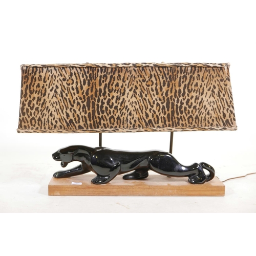 3 - A vintage porcelain table lamp in the form of a jaguar, mounted on a wood plinth, with faux hide sha... 