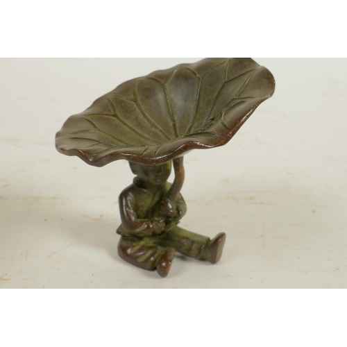 323 - A Chinese bronze figure of a seated boy holding a large lily leaf, 2½