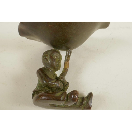 323 - A Chinese bronze figure of a seated boy holding a large lily leaf, 2½