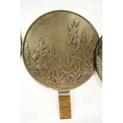 414 - Three earl C19th Japanese bronze hand mirrors, the backs decorated with flowers and calligraphy, lar... 