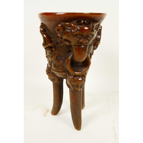 416 - A Chinese faux horn libation cup on three legs, embossed with mythical beasts