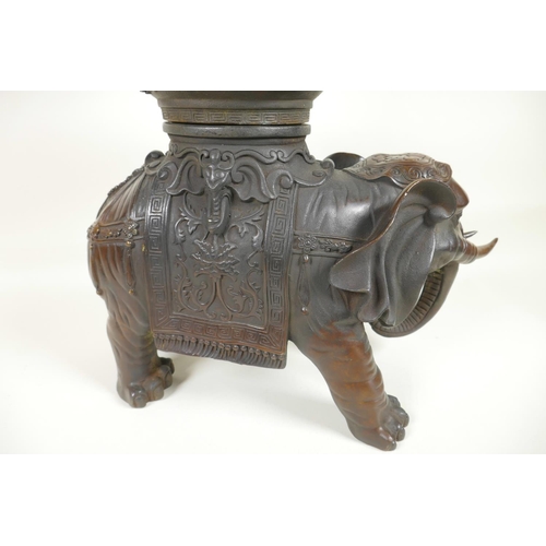 425 - An oriental bronze figure of an ornately dressed elephant with a large vase on his howdah, 16½