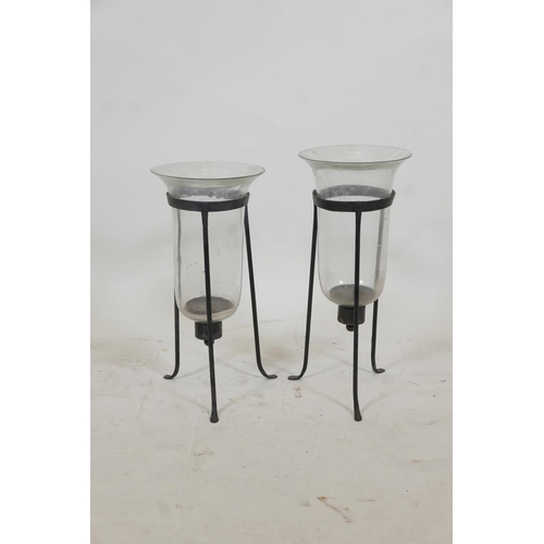 46 - A near pair of glass and wrought iron hurricane lanterns on tripod stands, 17½