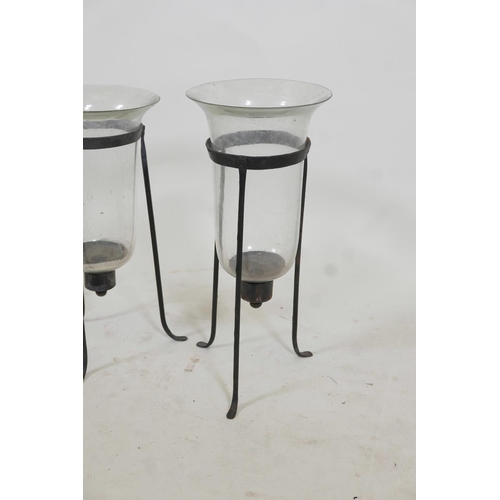 46 - A near pair of glass and wrought iron hurricane lanterns on tripod stands, 17½