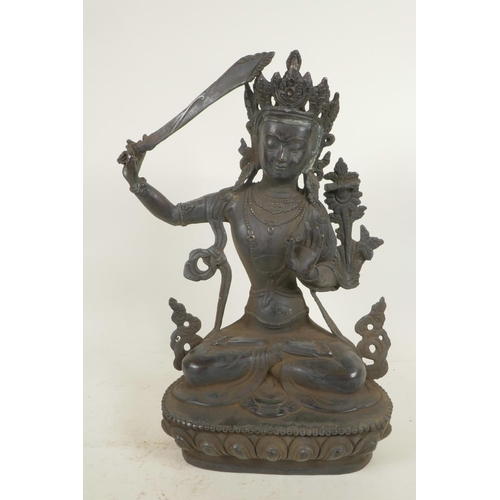 59 - A Chinese bronze figure of a Buddhist deity holding a sword and seated in meditation on a lotus thro... 