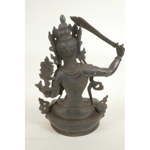 59 - A Chinese bronze figure of a Buddhist deity holding a sword and seated in meditation on a lotus thro... 