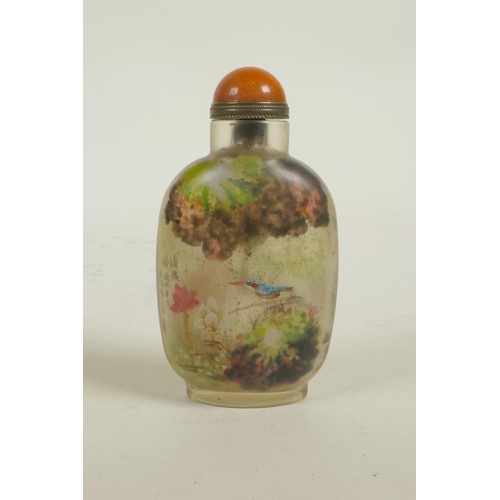 63 - A Chinese reverse decorated glass snuff bottle depicting figures in a mountain landscape and birds, ... 