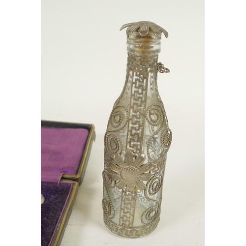 665 - A glass perfume bottle in a white metal wire work case, 5