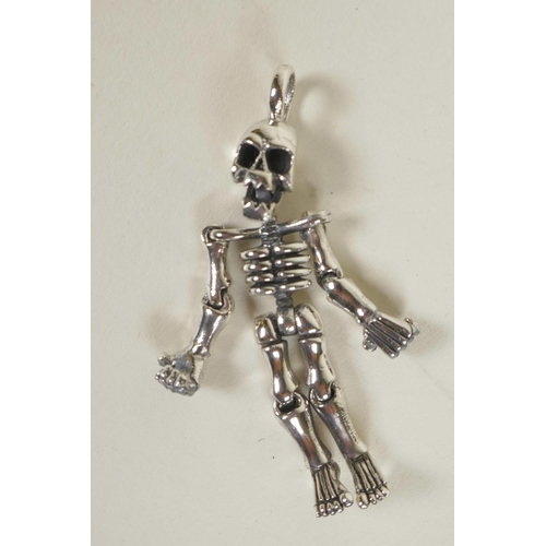 695 - A silver articulated pendant in the form of a human skeleton, 2