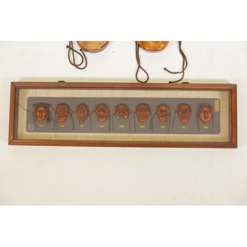 86 - Two Korean carved and painted wood masks and a framed set of similar miniature masks, 28