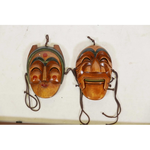 86 - Two Korean carved and painted wood masks and a framed set of similar miniature masks, 28