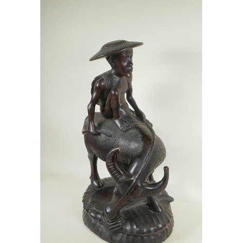 91 - An Oriental carved hardwood figure of a man seated on a buffalo, 23