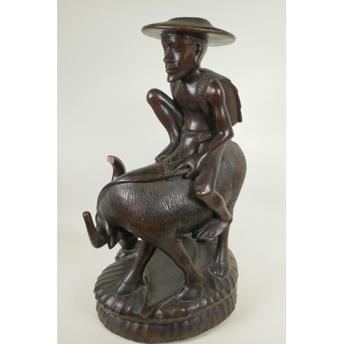 91 - An Oriental carved hardwood figure of a man seated on a buffalo, 23