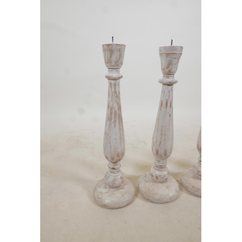 96 - A set of four turned and painted wood pricket candlesticks with a distressed finish, 19