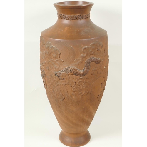 10 - A Japanese red earthenware urn shaped vase with embossed and carved decoration of dragons, 18½