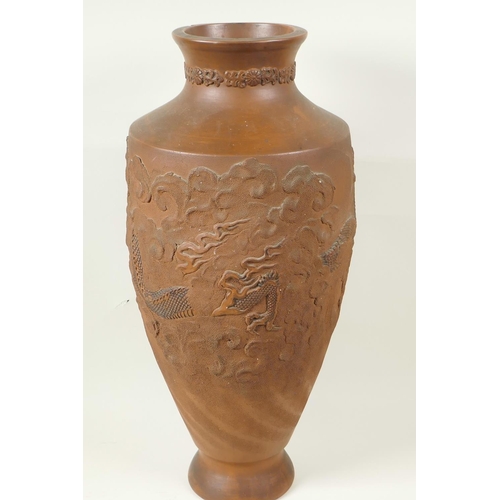 10 - A Japanese red earthenware urn shaped vase with embossed and carved decoration of dragons, 18½