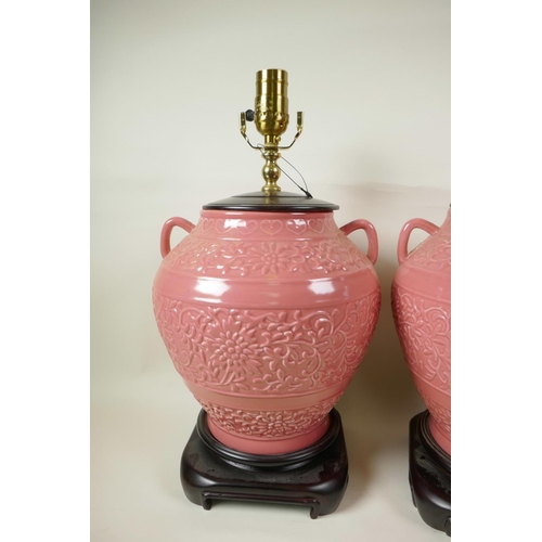 36 - A pair of Oriental style pink glazed porcelain table lamps in the form of bulbous two handled vases ... 