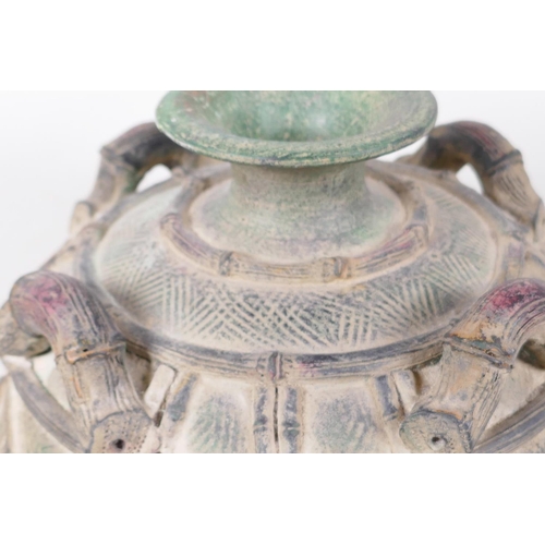 17 - An Oriental pottery vase with four handles modelled as bamboo, the body carved with monstera leaves,... 