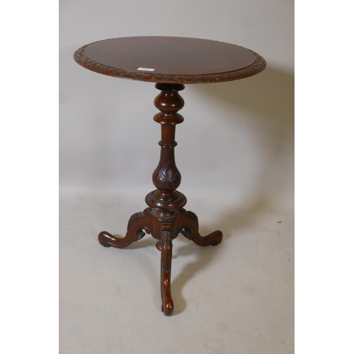 1217 - A Victorian figured walnut lamp table, the top with carved edge, raised on a turned baluster shaped ... 