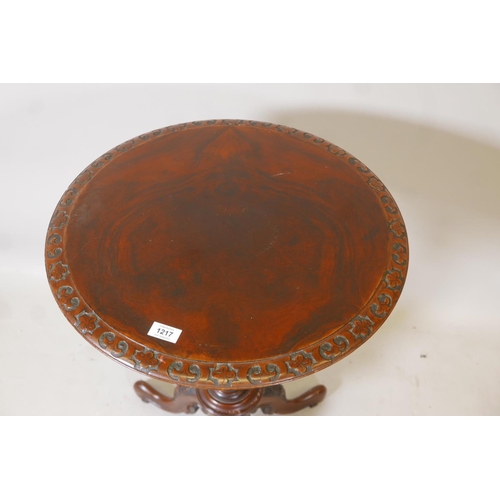 1217 - A Victorian figured walnut lamp table, the top with carved edge, raised on a turned baluster shaped ... 