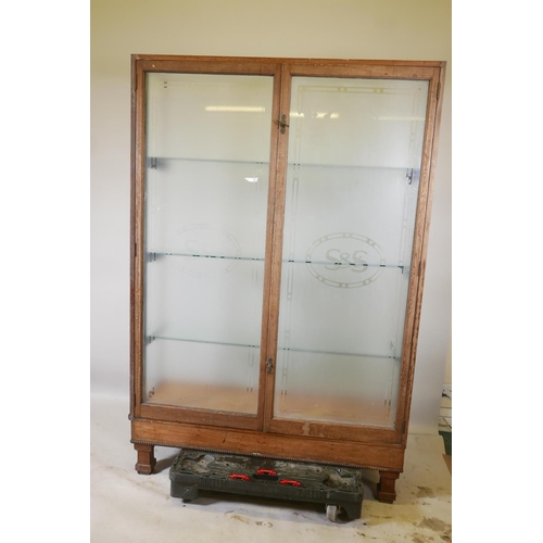 1228 - An early C20th shop display cabinet, the rear doors with etched decoration and company logo 