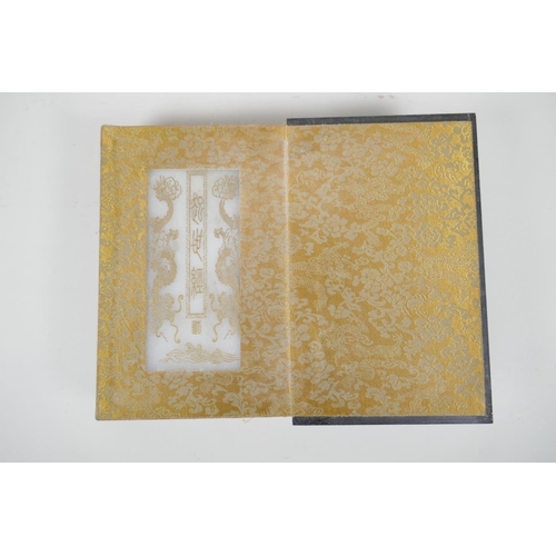 36 - A Chinese wood and material bound book containing white jade tablets with engraved and gilt characte... 