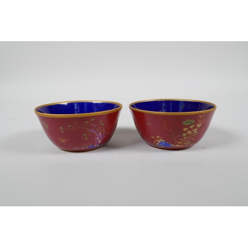 43 - A pair of Chinese red ground porcelain tea bowls with polychrome decoration of flowers, foliage and ... 