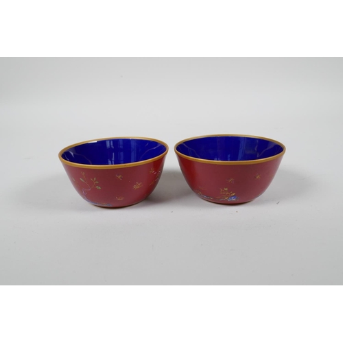 43 - A pair of Chinese red ground porcelain tea bowls with polychrome decoration of flowers, foliage and ... 