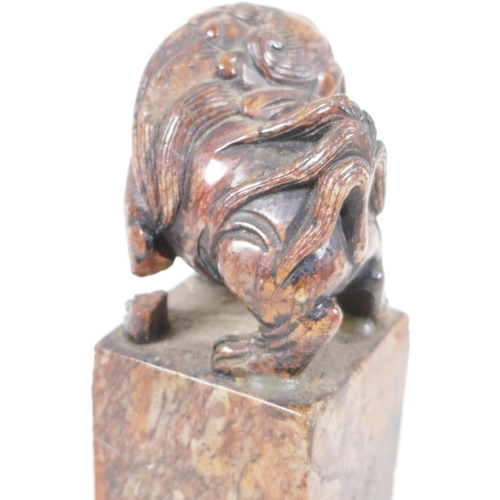 62 - An antique Chinese carved soapstone figure of a kylin standing on a square pedestal, A/F, 5