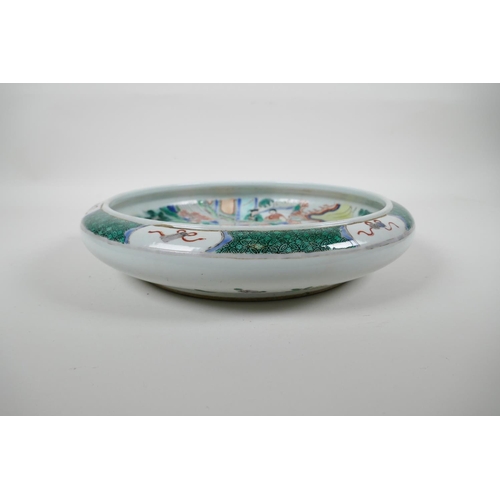 78 - A Chinese famille verte porcelain dish with a rolled rim decorated with warriors on horseback, 6 cha... 