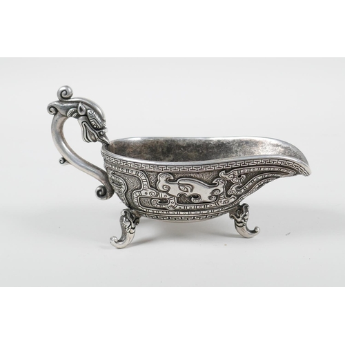 98 - A Chinese white metal libation cup with stylised dragon decoration and tripod feet, mark to base, 5&... 